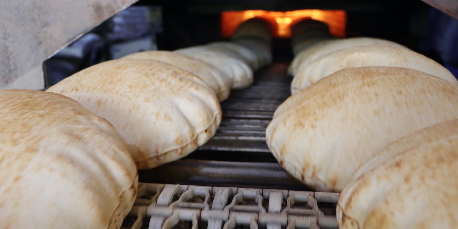 Baked bread comes out of the oven on a conveyor belt for cooling and packing